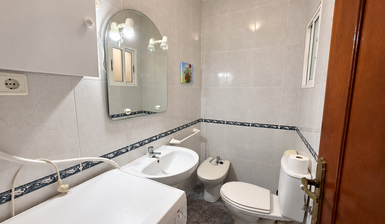 Baño compacto con lavadora y azulejos marmoleados